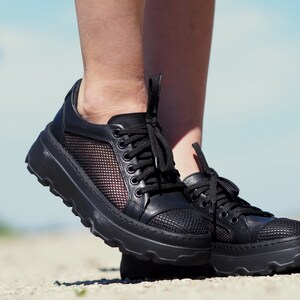 May include: Black leather sneakers with a mesh panel and a chunky platform sole.
