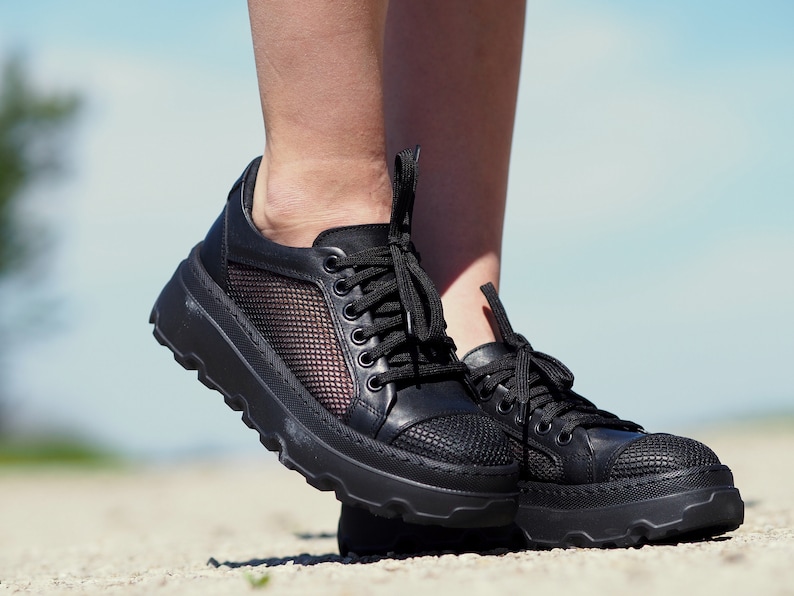 May include: Black leather sneakers with a mesh panel and a chunky platform sole.