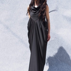 May include: A black maxi dress with a cowl neck and a flowing, draped skirt. The dress is sleeveless and has a relaxed fit.