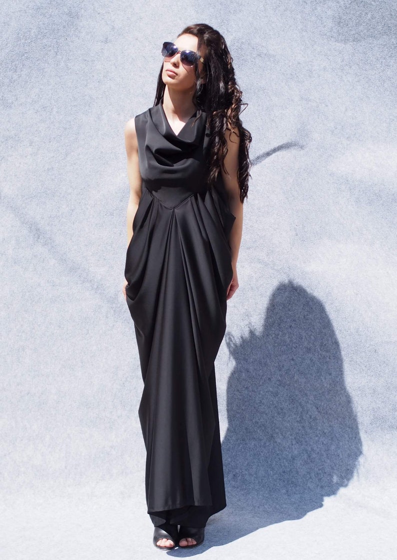 May include: A black sleeveless maxi dress with a cowl neck and a flowing, draped skirt. The dress is made of a soft, silky fabric and has a relaxed fit.