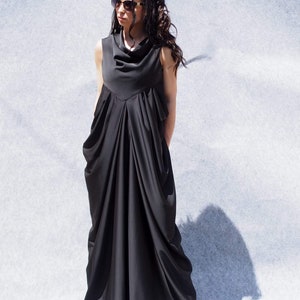 May include: A black sleeveless maxi dress with a cowl neck and a flowing, draped skirt. The dress is made of a soft, lightweight fabric.