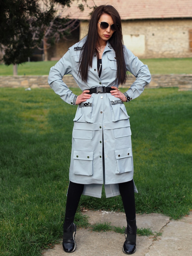 May include: A light blue long-sleeved jacket with a button-up front, multiple pockets, and a black belt. The jacket has black text that says "In Friend Fashion" on the front.