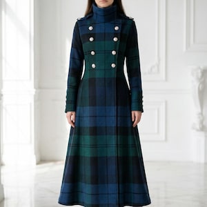 May include: A long, tartan coat in green, blue, and black. The coat has a double-breasted front with silver buttons, a high collar, and long sleeves. The coat is floor-length and has a flared skirt. The person is wearing blue heels.
