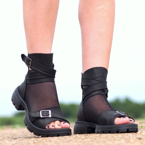 K&ouml;nnte beinhalten: Schwarze Ledersandalen mit einem Mesh-Einsatz und Schnallenverschluss. Die Sandalen haben eine dicke Plateau-Sohle.
