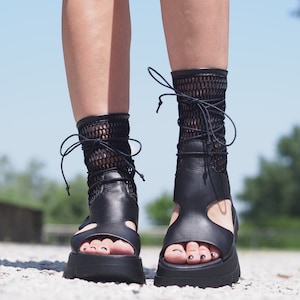 May include: Black leather sandals with a mesh ankle strap and a thick platform sole.