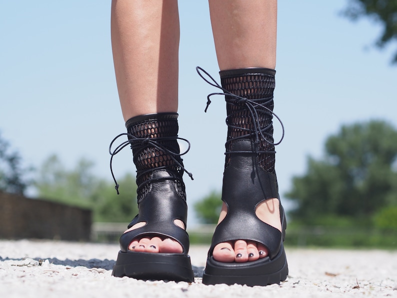May include: Black leather sandals with a mesh ankle strap and a thick platform sole.