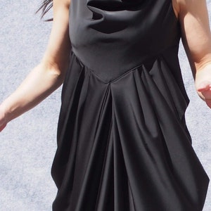 May include: A black sleeveless dress with a cowl neck and a flowing, draped skirt.