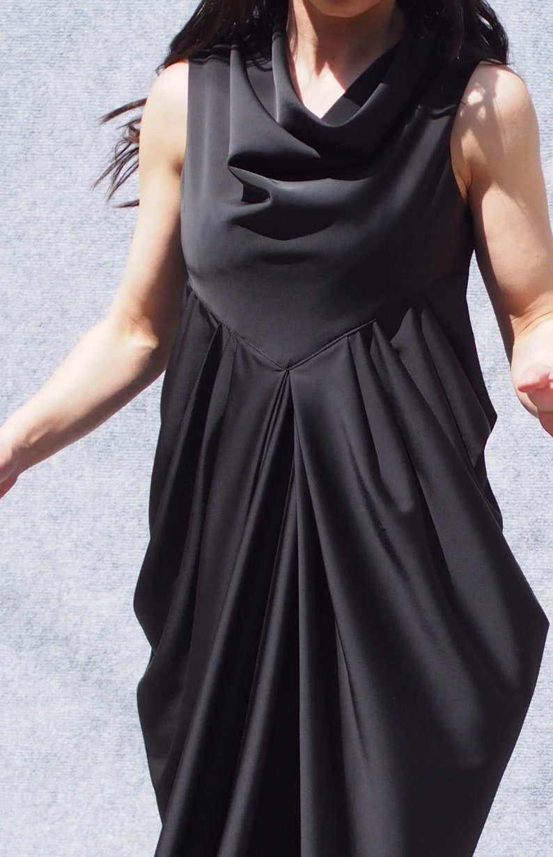 May include: A black sleeveless dress with a cowl neck and a flowing, draped skirt.