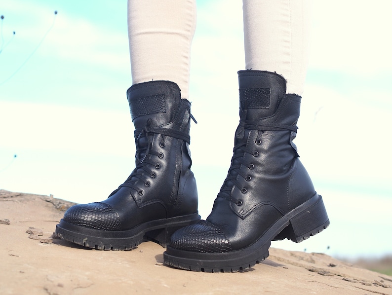 K&ouml;nnte beinhalten: Schwarze Leder-Stiefeletten mit Schn&uuml;rung und einem dicken Absatz. Die Stiefeletten haben ein strukturiertes Muster an der Spitze und einen Rei&szlig;verschluss an der Seite.
