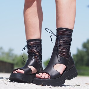 May include: Black leather platform sandals with a mesh ankle strap and lace-up closure.