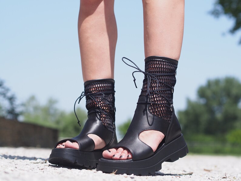 May include: Black leather platform sandals with a mesh ankle strap and lace-up closure.