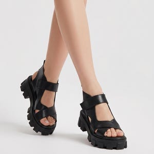 Pu&ograve; includere: Sandali in pelle nera con suola spessa e carrarmato. I sandali hanno pi&ugrave; cinturini e fibbie regolabili. Il design a punta aperta e la spessa suola platform conferiscono un look audace e moderno. Una scelta di calzature elegante.