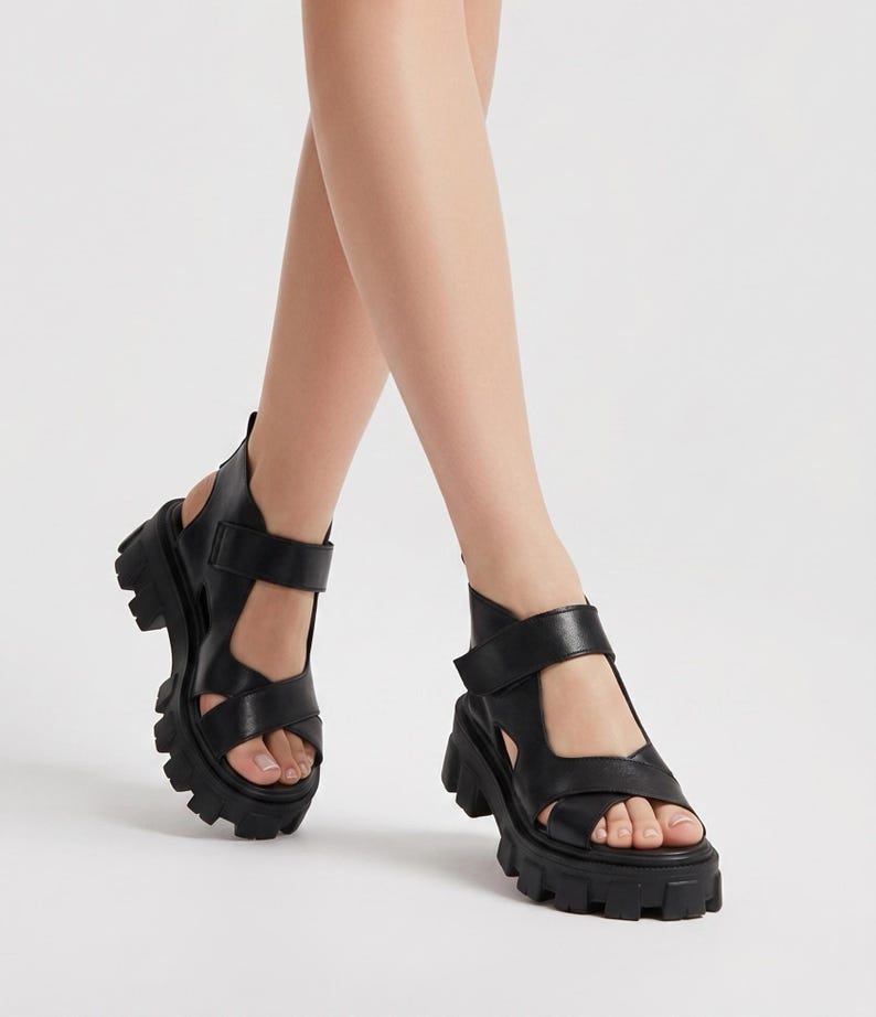 Pu&ograve; includere: Sandali in pelle nera con suola spessa e carrarmato. I sandali hanno pi&ugrave; cinturini e fibbie regolabili. Il design a punta aperta e la spessa suola platform conferiscono un look audace e moderno. Una scelta di calzature elegante.
