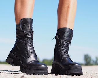 May include: A pair of black leather lace-up boots with chunky platform soles. The boots have a zip on the side and a decorative strap at the ankle.