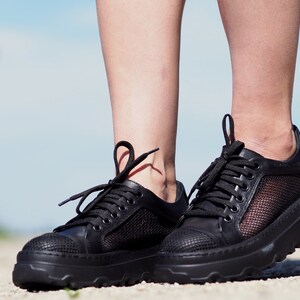 May include: Black leather sneakers with mesh panels and a chunky sole.
