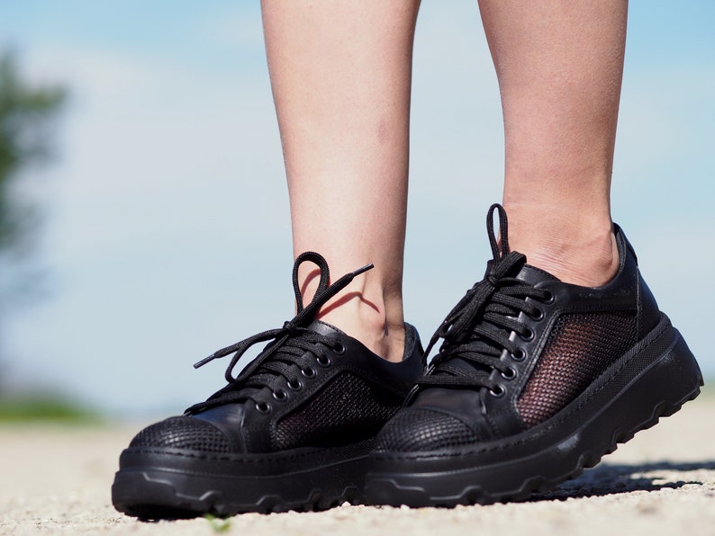 May include: Black leather sneakers with mesh panels and a chunky sole.
