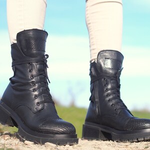 K&ouml;nnte beinhalten: Schwarze Schn&uuml;rstiefeletten aus Leder mit einem dicken Absatz und einem Schlangenhautmuster an der Spitze.