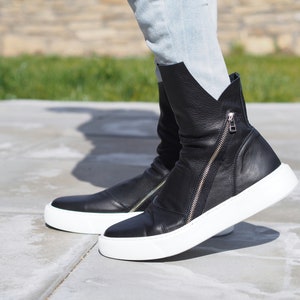 Puede incluir: Botas de tobillo de cuero negro con cremallera lateral y suela de plataforma blanca.