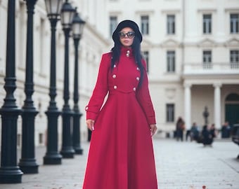 Puede incluir: Un abrigo largo de color rojo vibrante con cuello alto, frente de doble botonadura con botones plateados y mangas largas con puños abotonados. El abrigo tiene un corpiño ajustado que se ensancha en una falda larga, junto con un sombrero negro.