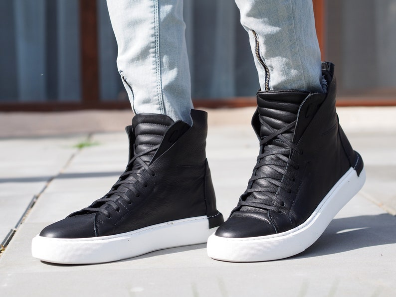 May include: Black leather high-top sneakers with white soles. The sneakers have a zipper on the side and are laced up.