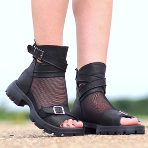K&ouml;nnte beinhalten: Schwarze Ledersandalen mit einem Mesh-Einsatz und Schnallenverschl&uuml;ssen. Die Sandalen haben eine dicke Plateau-Sohle.
