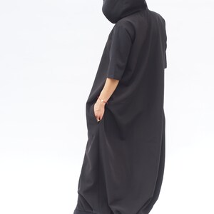 Puede incluir: Un vestido maxi negro con capucha, falda larga y fluida y mangas cortas. El vestido est&aacute; hecho de una tela suave y c&oacute;moda y tiene un corte holgado.