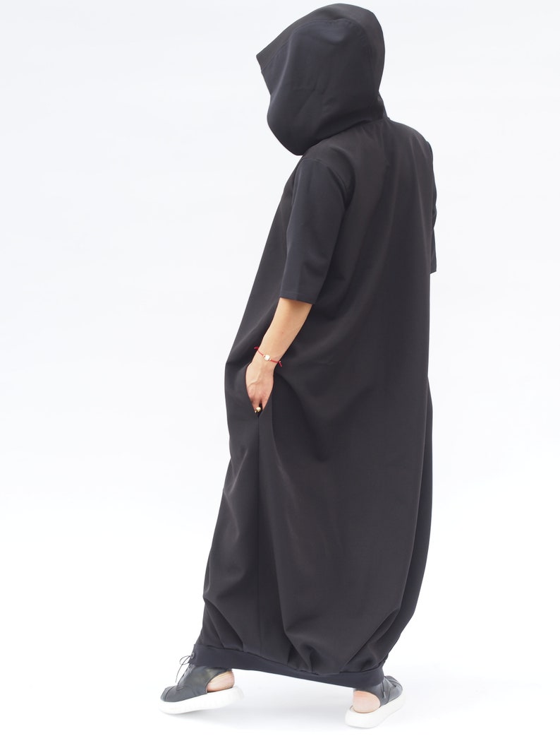 Puede incluir: Un vestido maxi negro con capucha, falda larga y fluida y mangas cortas. El vestido est&aacute; hecho de una tela suave y c&oacute;moda y tiene un corte holgado.