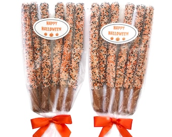 May include: Two packages of six pretzel rods dipped in chocolate and covered in orange and black sprinkles. Each package has a "Happy Halloween" label with a pumpkin graphic.