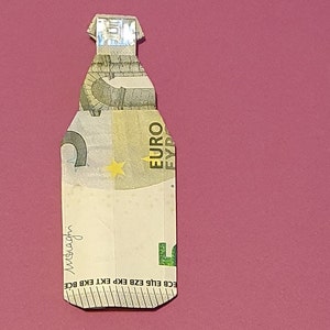 Op de afbeelding: Een briefje van vijf euro gevouwen in de vorm van een fles. Het briefje is groen en wit met een ster en het woord "EURO" erop gedrukt. Het briefje is gevouwen om een flesvorm te cre&euml;ren met een nek en een dop.