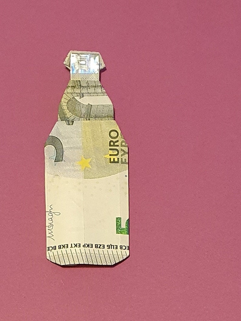 Op de afbeelding: Een briefje van vijf euro gevouwen in de vorm van een fles. Het briefje is groen en wit met een ster en het woord "EURO" erop gedrukt. Het briefje is gevouwen om een flesvorm te cre&euml;ren met een nek en een dop.