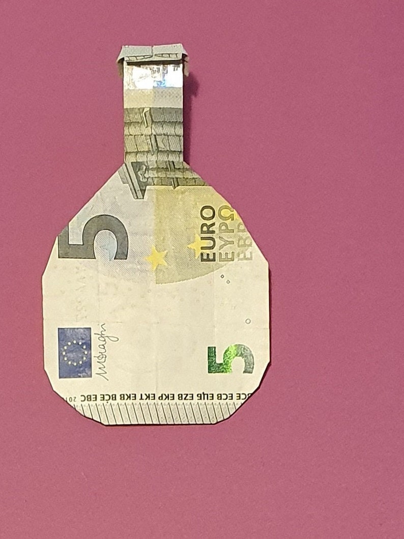 Op de afbeelding: Een 5 eurobiljet gevouwen in de vorm van een fles. Het biljet is groen en wit met een ster en het woord "EURO" erop gedrukt.