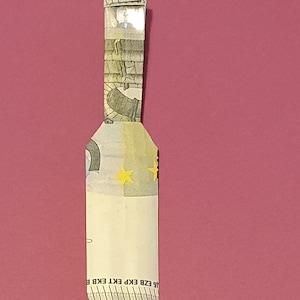 Op de afbeelding: Een gevouwen eurobiljet met een geel sterrendesign en de tekst "&Epsilon;&Kappa;&Tau; ECB EKP EKT EZB BCE" onderaan.