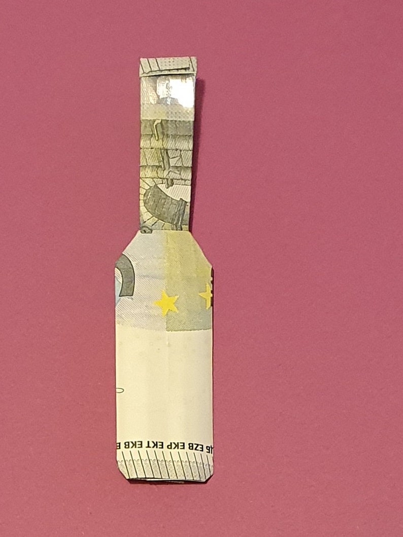 Op de afbeelding: Een gevouwen eurobiljet met een geel sterrendesign en de tekst "&Epsilon;&Kappa;&Tau; ECB EKP EKT EZB BCE" onderaan.