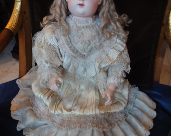 May include: A porcelain doll with blonde hair and blue eyes, wearing a white lace dress with a ruffled skirt.