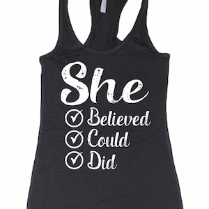 Puede incluir: Camiseta de tirantes negra con un gr&aacute;fico blanco que dice "She Believed Could Did" con marcas de verificaci&oacute;n junto a cada palabra.