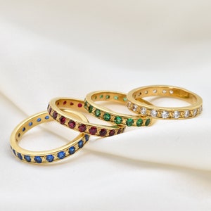 Peut inclure: Quatre bagues empilables en or avec des pierres précieuses de différentes couleurs. Les bagues sont serties de pierres bleues, rouges, vertes et transparentes.