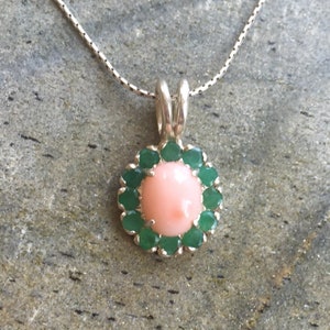 May include: A silver necklace with a pink coral pendant surrounded by a halo of green gemstones.