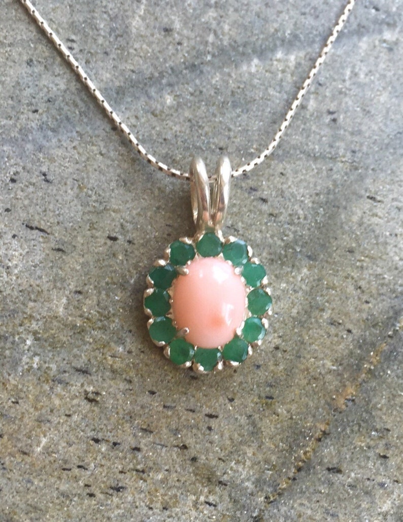May include: A silver necklace with a pink coral pendant surrounded by a halo of green gemstones.
