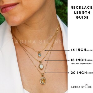 Puede incluir: Una gu&iacute;a de longitud de collares con tres cadenas doradas y colgantes ovalados de distintos tama&ntilde;os. Las etiquetas indican longitudes de 16 pulgadas (40 cm), 18 pulgadas (45 cm) y 20 pulgadas (50 cm). La marca Adina Stone es visible.