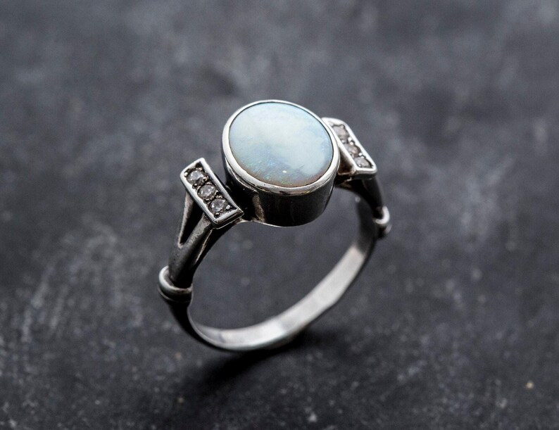 May include: A silver ring with a white opal gemstone and small diamonds on the band.