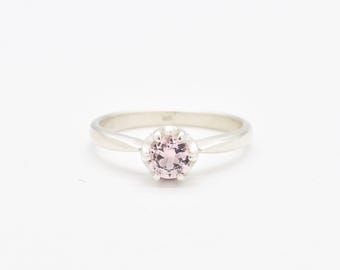 May include: A silver ring with a pink gemstone set in a prong setting.