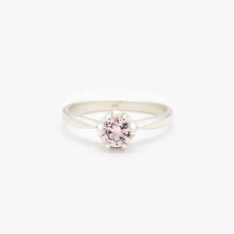May include: A silver ring with a pink gemstone set in a prong setting.