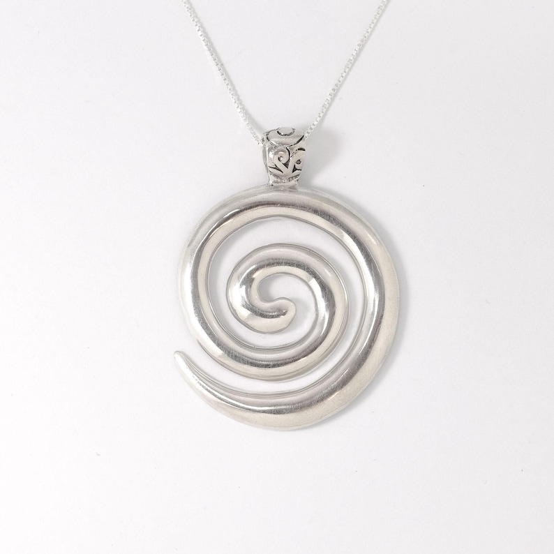 May include: A silver spiral pendant necklace. The pendant is a large, open spiral design.