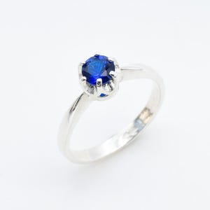 Puede incluir: Un anillo de plata con una piedra preciosa azul engastada en garras.
