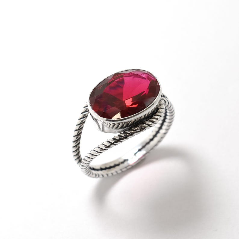 Peut inclure: Une bague en argent avec une bande torsad&eacute;e et une grande pierre rouge de forme ovale.
