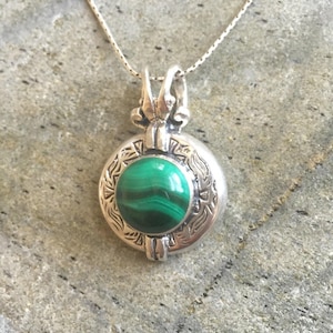 May include: A silver necklace with a round pendant featuring a green malachite stone set in a detailed silver frame.