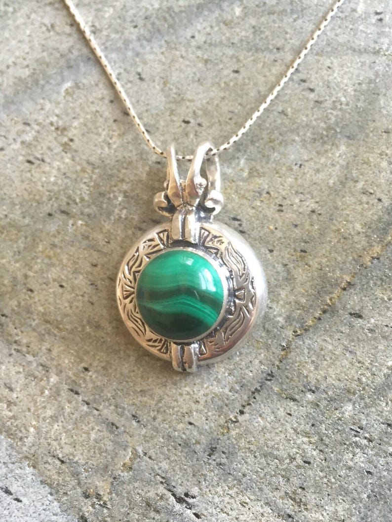 May include: A silver necklace with a round pendant featuring a green malachite stone set in a detailed silver frame.