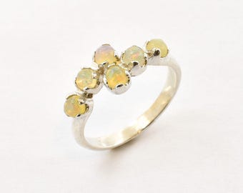 Pode incluir: Anel de prata com seis opalas ovais. As opalas são amarelo-pálido com tons alaranjados, engastadas em biséis individuais. A banda do anel é lisa e polida. Um design simples e elegante, adequado para uso diário ou ocasiões especiais.