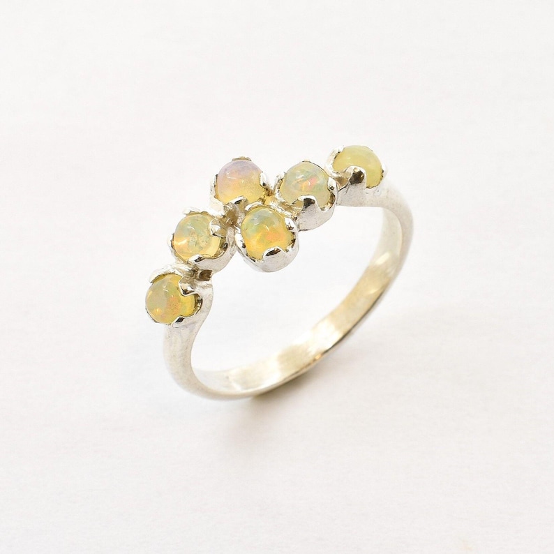 Puede incluir: Anillo de plata con seis &oacute;palos ovalados. Los &oacute;palos son de color amarillo p&aacute;lido con matices anaranjados, engastados en biseles individuales. La banda del anillo es lisa y pulida. Un dise&ntilde;o sencillo y elegante para cualquier ocasi&oacute;n.