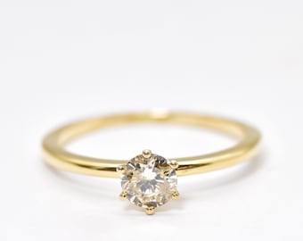 May include: A simple gold band ring with a single round diamond set in a six-prong setting.